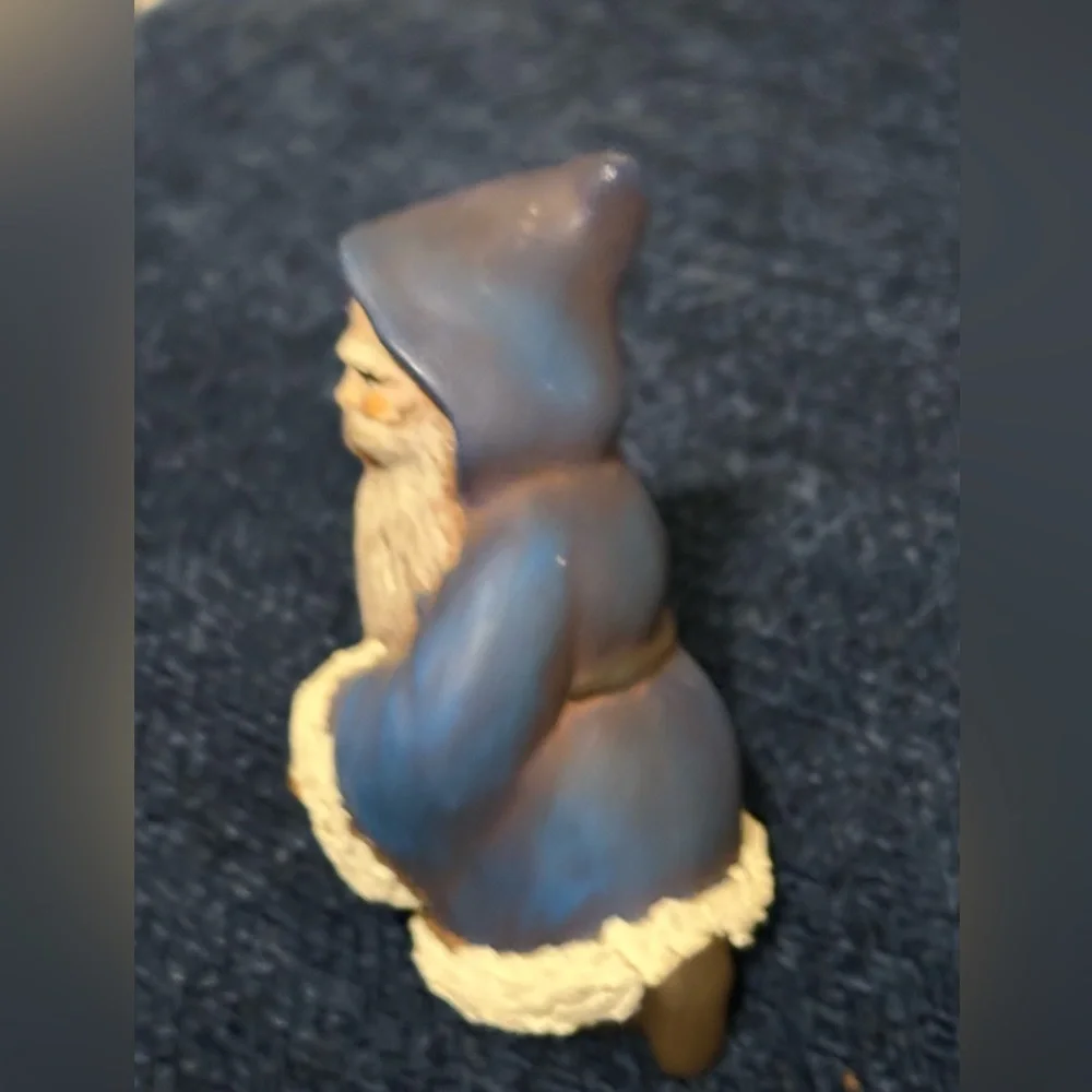 Cute blue robed kneeling Santa. He carries a basket of gifts.